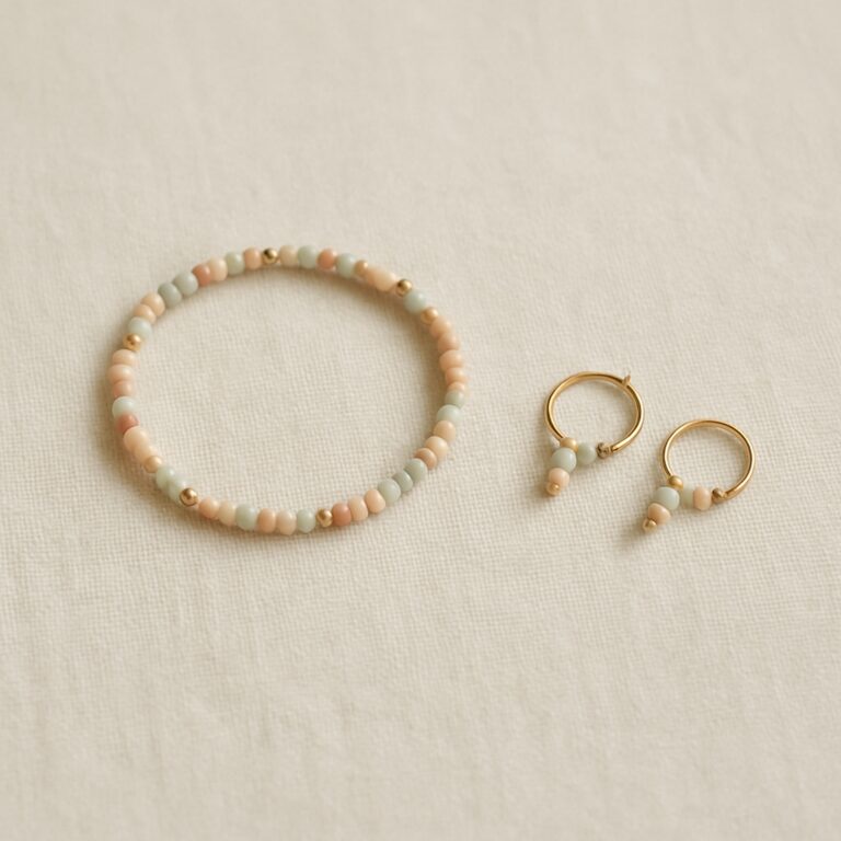 Мінімалістичне flat-lay: делікатний браслет і невеликі сережки - перші прикраси з бісеру на бежевому льняному фоні, пастельні тони і золоті акценти